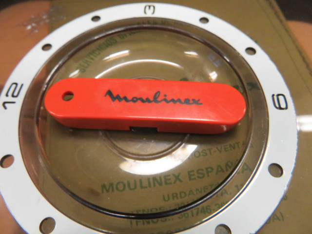 Yaourtière type 508, de forme ronde, orange et blanche avec un couvercle en plastique transparent brun fumé. Elle est accompagnée de 5 pots ronds en verre à couvercle en plastique blanc (1970) (métal, plastique, verre),Alençon Moulinex, Poids 1,4 kg, 9 pièces, don de l'association Moulinex Jean Mantelet.