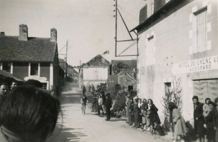 Course cycliste à La Roche-Mabile, Rémy Claire, club sportif d'Alençon (CSA), passage devant l'Hôtel du Chêne Vert A. Coupard), photographie noir et blanc, DR, collection particulière I. Houlette, B. Morel, 2024, AMA.