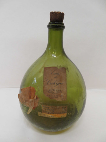 Bouteille en verre avec étiquette "Eau de Cologne supérieure, Madeleine Pesche", "Recette de fabrication"(Haut : 34cm, contenance : 5 litres).