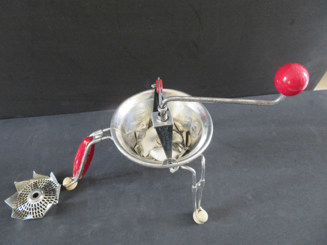 "Moulinette" P3 à pression variable, grilles (manque la grille n°1), manche boule rouge, avec carton (Acier, bois, caoutchouc), Moulin-Légumes,notice, 5 pièces, don de l'association Moulinex Jean Mantelet.