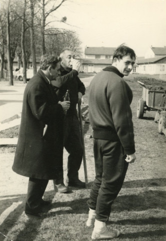Stade Jacques Fould, installation d'une piste stabilisée pour les entraînements d'hiver en remplacement de la piste cendrée (revêtement est composé d'un mélange de sable et de cendre ou de mâchefer), (à droite) Michel Estivalet, M. Estivalet père, bâtiment occupé par les enfants du centre aéré du bois d'Hesloup, transformé ensuite en salle d'haltérophilie et de boxe, photographie noir et blanc, phot. Claude Varnier collection particulière Thierry Varnier, 2024, AMA.