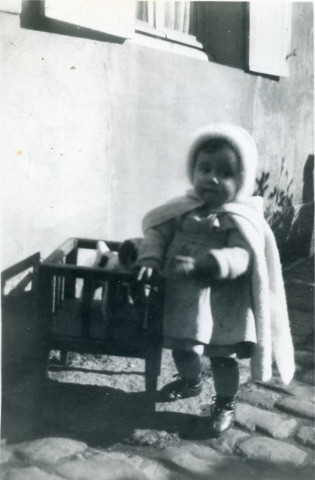 Maryvonne Thoréton avec son petit banc et son chien en tissu, sous la fenêtre de la rue Candie : photographie noir et blanc, DR, 6 x 8.8, (12 février 1950),(collection particulière Maryvonne Thoréton, AMA, 2018.)