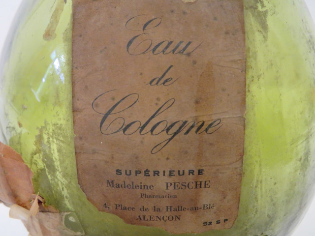 Bouteille en verre avec étiquette "Eau de Cologne supérieure, Madeleine Pesche", "Recette de fabrication"(Haut : 34cm, contenance : 5 litres).