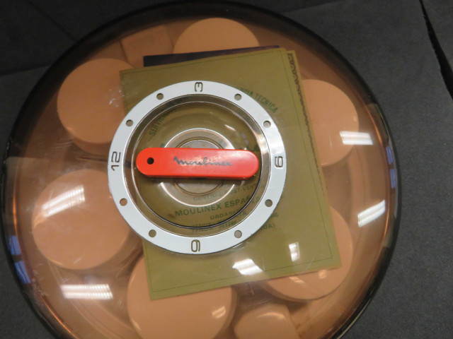 Yaourtière type 508, de forme ronde, orange et blanche avec un couvercle en plastique transparent brun fumé. Elle est accompagnée de 5 pots ronds en verre à couvercle en plastique blanc (1970) (métal, plastique, verre),Alençon Moulinex, Poids 1,4 kg, 9 pièces, don de l'association Moulinex Jean Mantelet.