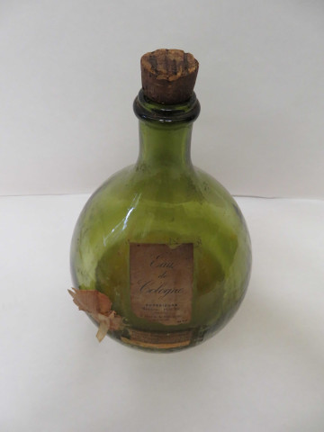 Bouteille en verre avec étiquette "Eau de Cologne supérieure, Madeleine Pesche", "Recette de fabrication"(Haut : 34cm, contenance : 5 litres).