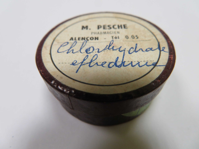 Boîtes pharmaceutiques circulaires de Madeleine Pesche (couleur : marron) avec étiquette blanche (diam : 3.7cm, haut : 1.7cm) (1950-1980).